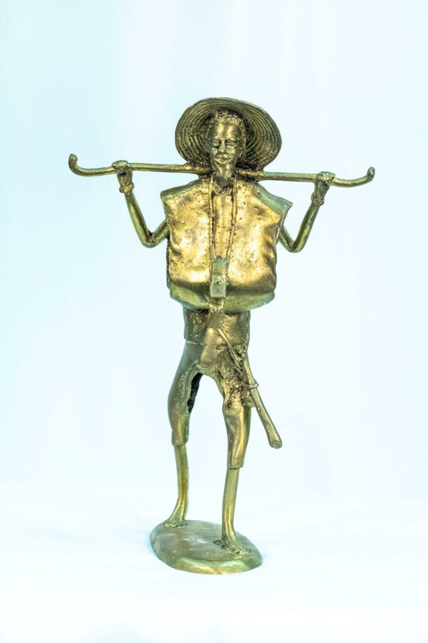 figurine, brass man holding staff over his shoulders, front