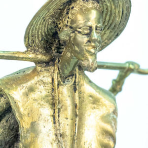 figurine, brass man holding staff over his shoulders, closeup