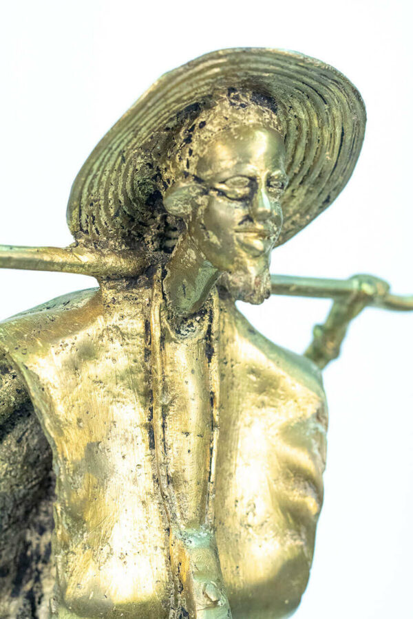 figurine, brass man holding staff over his shoulders, closeup