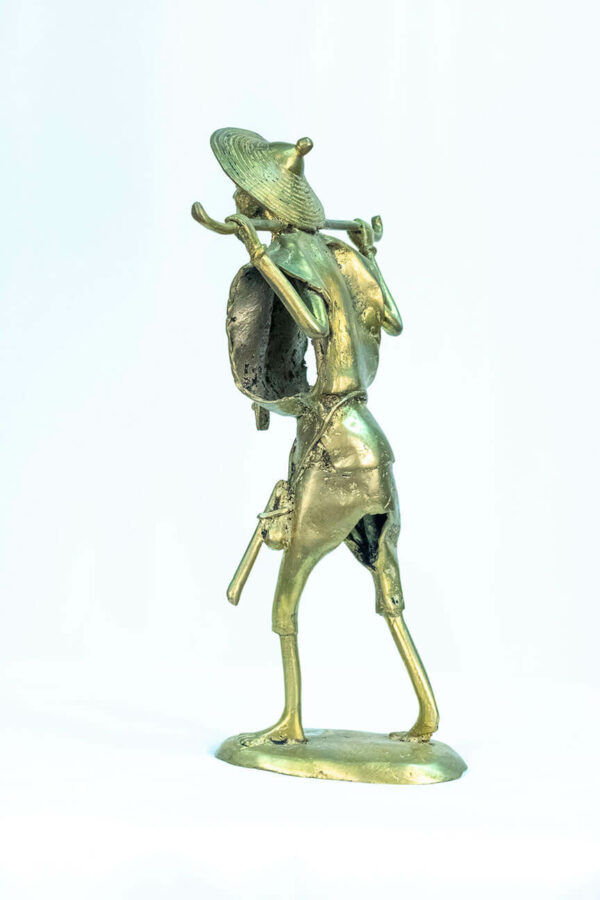 figurine, brass man holding staff over his shoulders, left