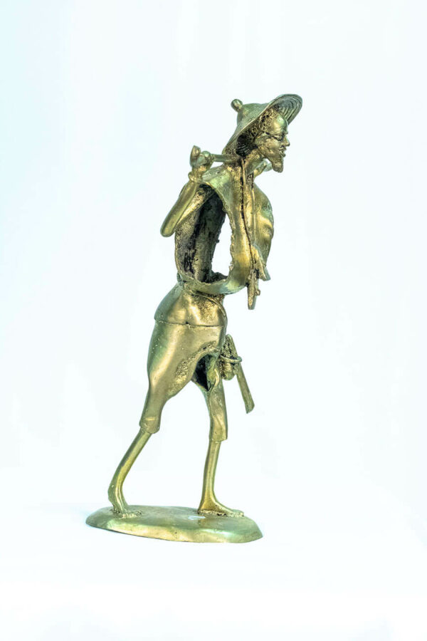 figurine, brass man holding staff over his shoulders, right