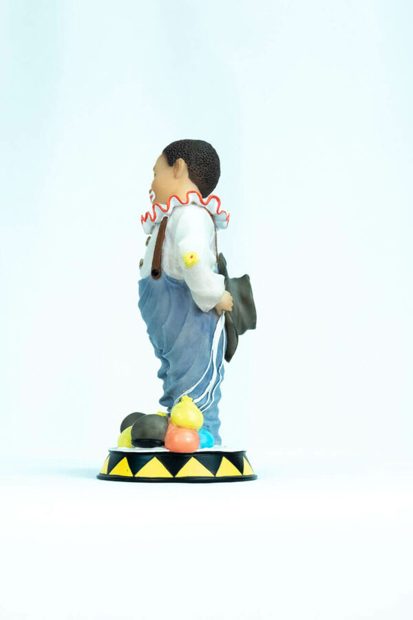 clown figurine, child clown in baggy blue pants, left