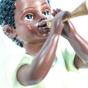 figurine, angel sitting on rock blowing horn, closeup