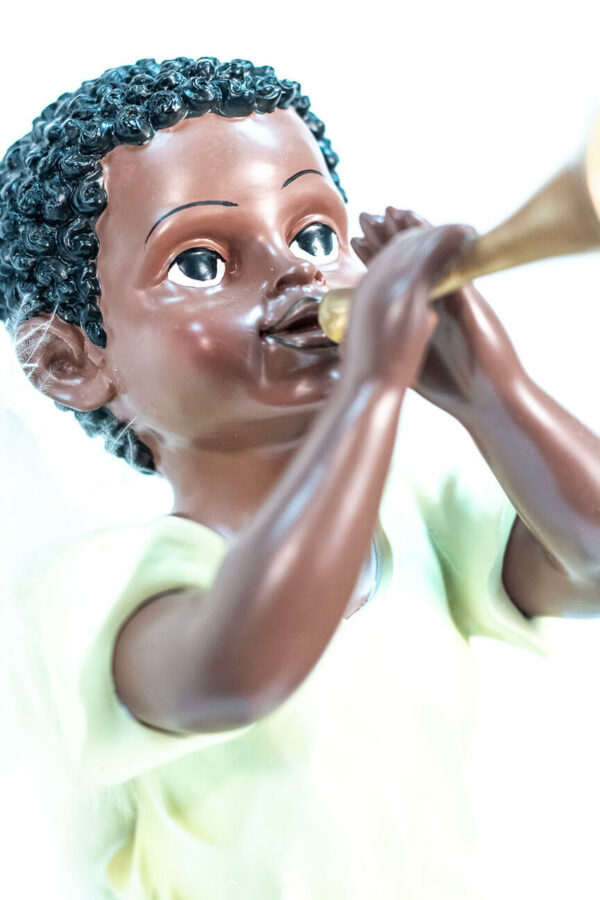 figurine, angel sitting on rock blowing horn, closeup